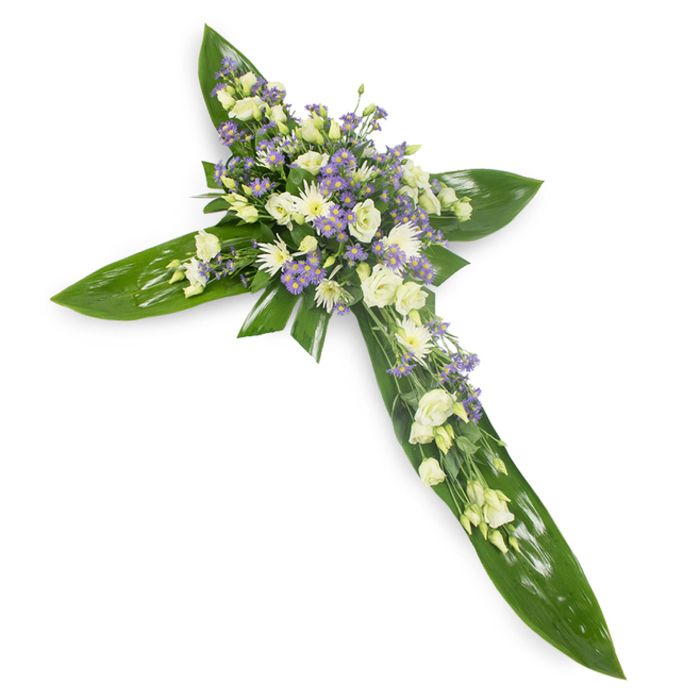 This floral cross, photographed on a clean white field from a slight overhead angle, reads as both a symbol and a tactile embrace. The structural base is an artful lattice of large tropical leaves-Ti leaves whose glossy, deep-green surfaces and pronounced veins form the defined outline of the cross. At the meeting point and flowing along each arm, clusters of soft, ivory and white lisianthus unfold in layers, their velvety petals creating a sense of purity and gentle dignity. Interspersed are small, white chrysanthemum blooms that add compact, luminous texture, while sprays of tiny lavender or pale purple flowers-limonium or small asters-provide a subtle, cool contrast that deepens the visual field. Delicate green filler foliage is threaded through the blooms, lending a natural, garden-like softness against the leaves' sleekness. The lighting is calm and even, revealing the tonal nuances of cream, white, and lavender while keeping shadows minimal so the composition reads cleanly and respectfully. There is a faint, fresh-frond scent and a whisper of floral sweetness that together create a comforting atmosphere. This is a classic sympathy arrangement conceived for memorial gatherings, graveside services, or church altars in and around St Mary Cray and the Cray Valley; it communicates reverence, solace, and the quiet hope of lasting remembrance, crafted with the restraint and care befitting moments of farewell.